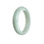 A close-up photo of a half-moon shaped pale green jade bracelet. The bracelet has a smooth and glossy surface, showcasing the natural beauty of the jade. The color is a delicate shade of green, giving the bracelet an elegant and timeless appeal. The bracelet has a high-quality grade A jade, known for its exceptional clarity and durability. It is a stunning piece of jewelry that exudes sophistication and style.