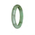 A close-up of a green jade bracelet with a semi-round shape, showcasing its natural beauty and traditional design.
