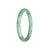 A small, round jade bracelet with a light green color and a unique pattern.