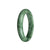 A close-up photo of a beautiful green patterned Burma Jade bangle with a half-moon shape, showcasing its natural and unique design.