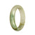 A half-moon shaped Burmese jade bangle featuring a certified natural light green and white pattern.