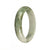 A close-up image of an elegant jade bangle bracelet with a white base and a beautiful green pattern. The bracelet is made of authentic Type A Burma Jade and has a unique 56mm half moon shape. Perfect for adding a touch of sophistication to any outfit.