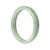 A half-moon shaped, light green jade bangle bracelet with a polished finish.